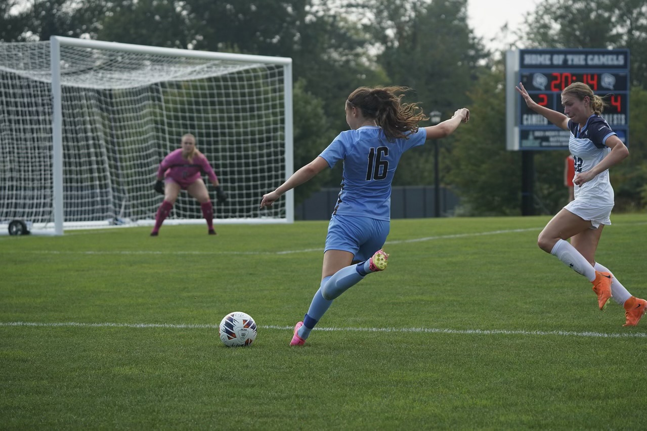 Thalia Greenberg, number 16 in light blue, striking a shot at goal for Tufts at Connecticut College